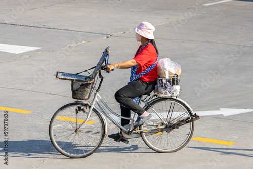 A lottery saleswoman rides a bicycle, Thailand photo