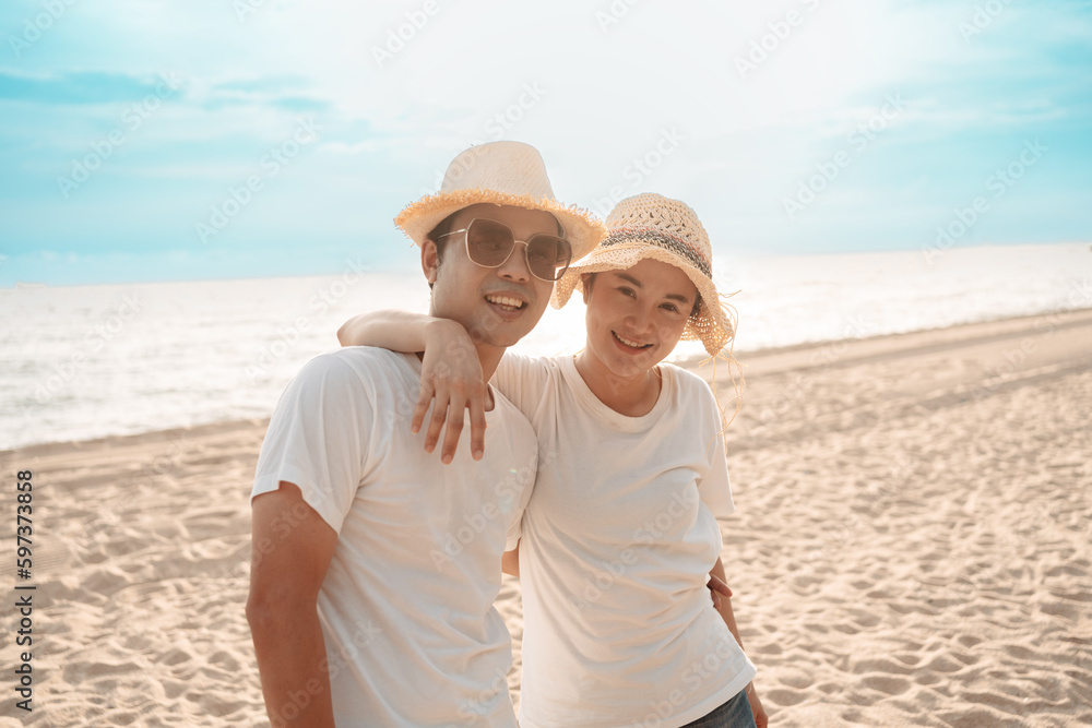 Asian couple travel on the beach smiling freedom at sunset on weekend activity lifestyle.