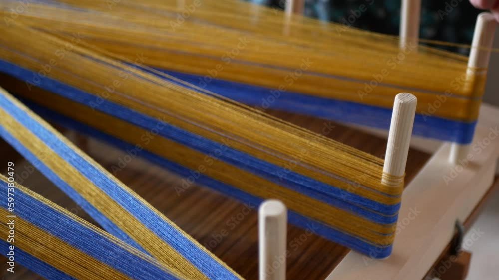 Person is winding a warp for the weaving loom using warping frame and