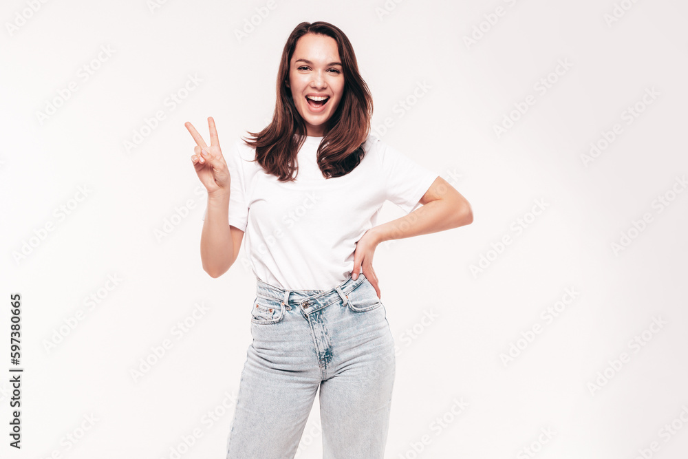 Young beautiful woman. Trendy carefree model in casual summer white T-shirt and blue jeans. Positive female isolated on white in studio. Cheerful and happy. Copy space, mockup. Shows peace sign Young beautiful woman. Trendy carefree model in casual summer white T-shirt and blue jeans. Positive female isolated on white in studio. Cheerful and happy. Copy space, mockup. Shows peace sign