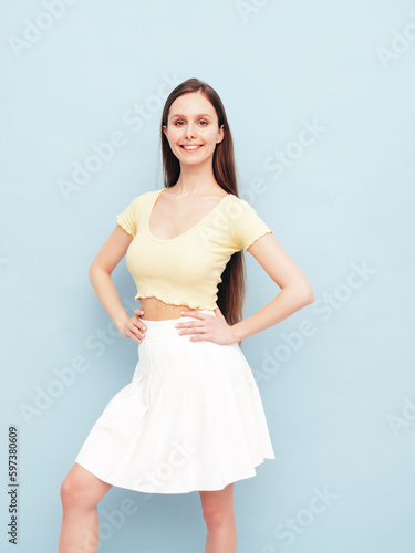 Image portrait of optimistic woman in yellow t-shirt and white skirt. Carefree stylish model with long hair. Smiling female posing in studio. Isolated. Looks delightful and cute. Slim