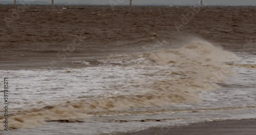 wide shot of cold bleak looking winter waves breaking on to Ingoldmells, Skegness sandy beach photo