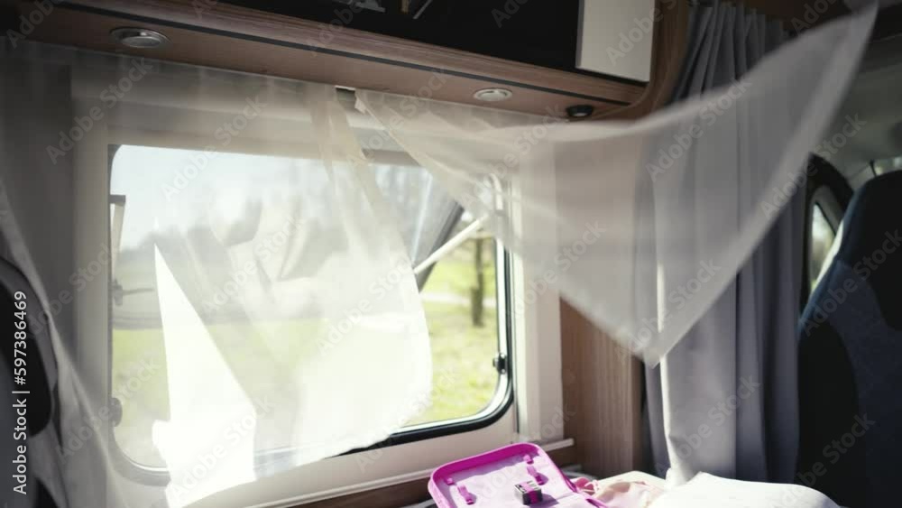 Wind plays with the curtains at the open window of a camper parked in the countryside Wind plays with the curtains at the open window of a camper parked in the countryside