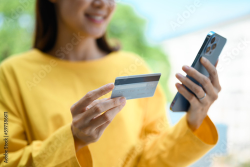 Young woman hand holding credit card and using smartphone for payment online or checking her bank account
