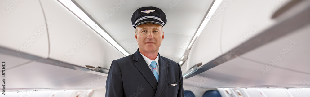 Male pilot standing in passenger airplane cabin Male pilot standing in passenger airplane cabin