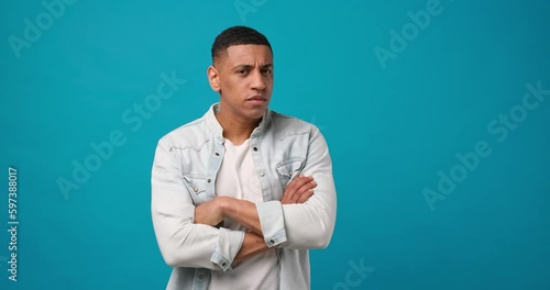 Young african american man listening to somebody talks and looking at the camera with suspicion and distrust
