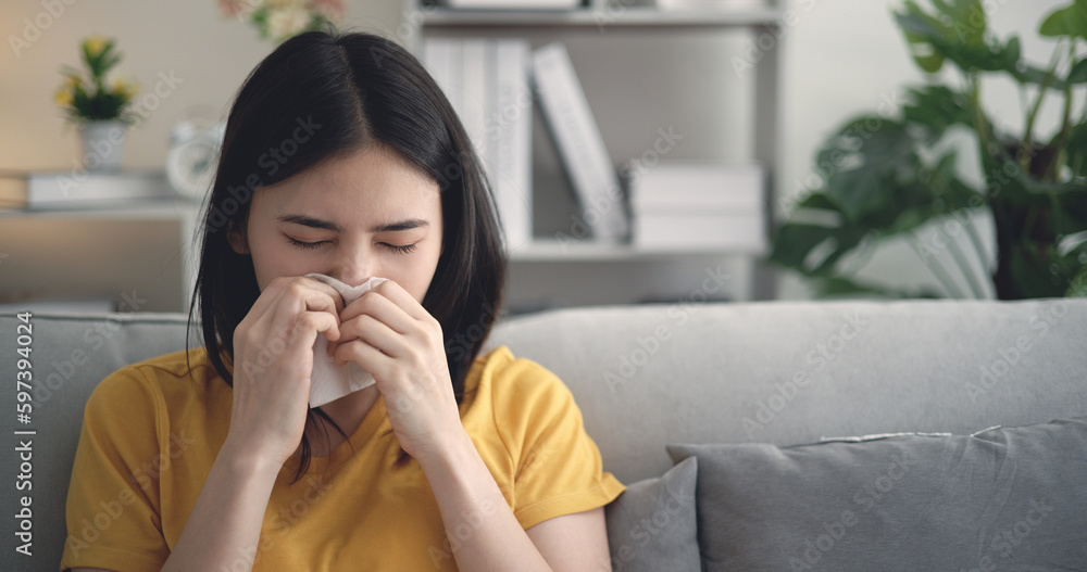 Asian Young woman fever sneeze in blowing her nose in paper tissue at home Asian Young woman fever sneeze in blowing her nose in paper tissue at home