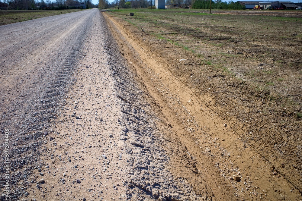 Drainage ditch along the road. View of the roadside, along which a deep ditch was dug to drain rainwater. Road reconstruction. Latvia Drainage ditch along the road. View of the roadside, along which a deep ditch was dug to drain rainwater. Road reconstruction. Latvia
