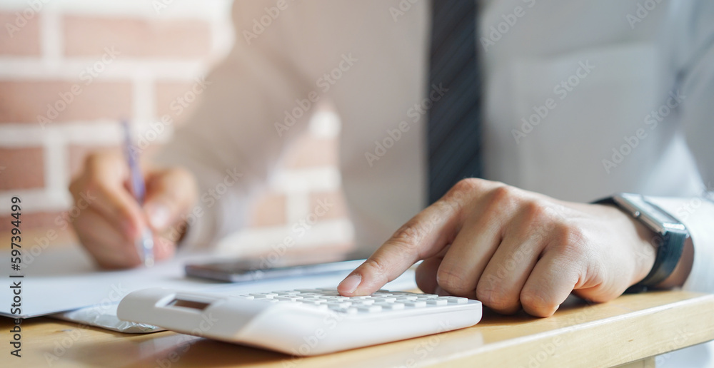 Obraz premium close up banker employee man press on calculator to check about profit or financial annual of company in room for business concept