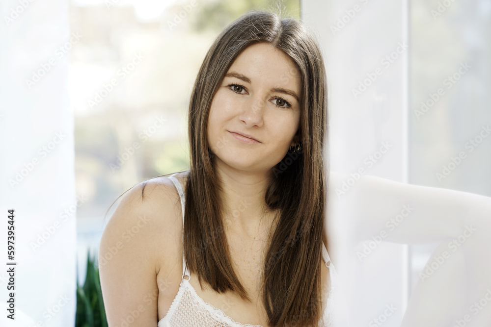 Portrait of a beautiful happy smiling woman in front of a window