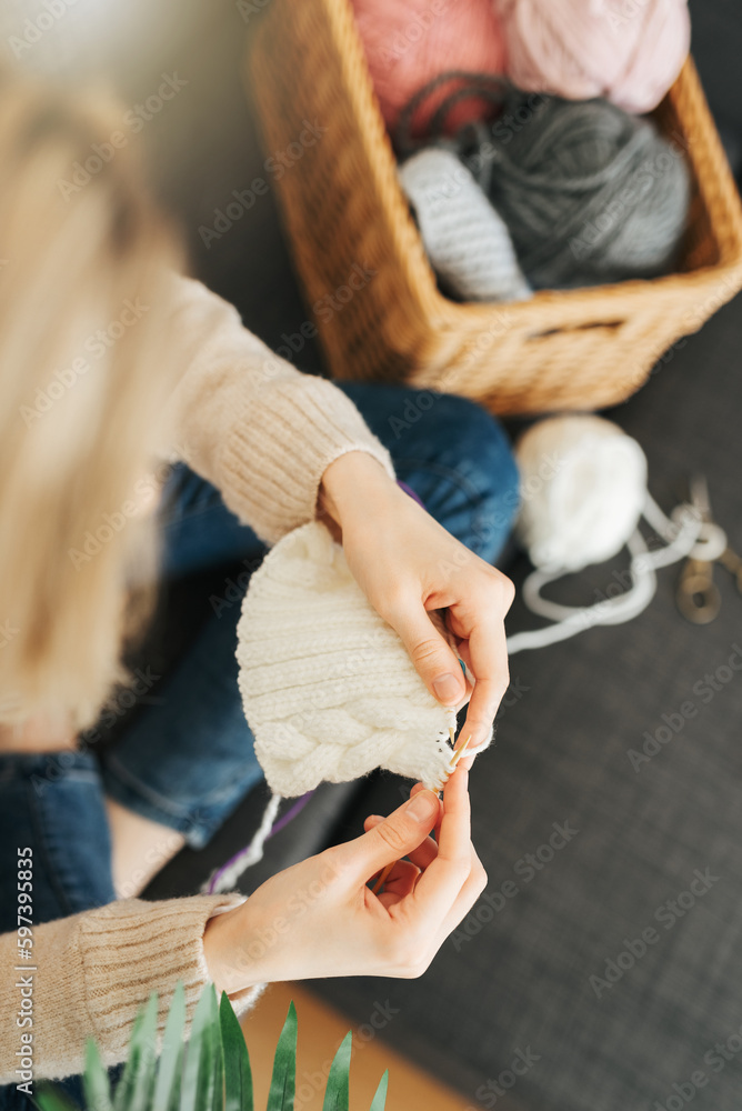 Naklejka premium Young woman knitting warm scarf indoors