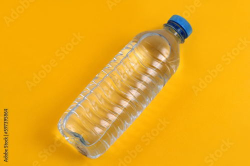 Bouteille d'eau minérale en plastique en gros plan sur fond jaune