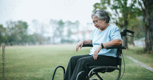 Foto Mature woman in wheelchair having knee pain with pain expression on face