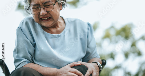 Fotografía Mature woman in wheelchair having knee pain with pain expression on face