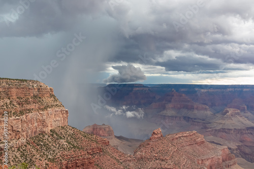 Dark clouds emerging to rain storm seen from the Bright Angel Point at South Rim of Grand Canyon National Park, Arizona, USA. Isolated summer cloudburst. Colorado River weaving through rugged terrain