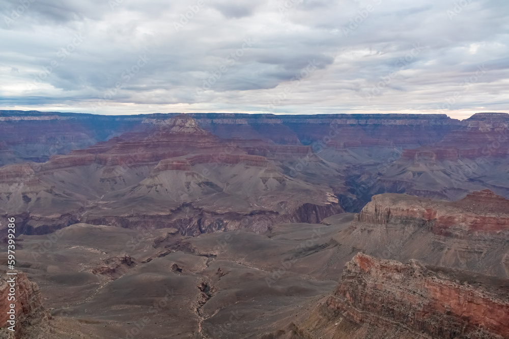 Panoramic aerial view from South Kaibab hiking trail at South Rim of Grand Canyon National Park, Arizona, USA, America. Colorado River weaving through valleys and rugged terrain. Clouds and overcast.