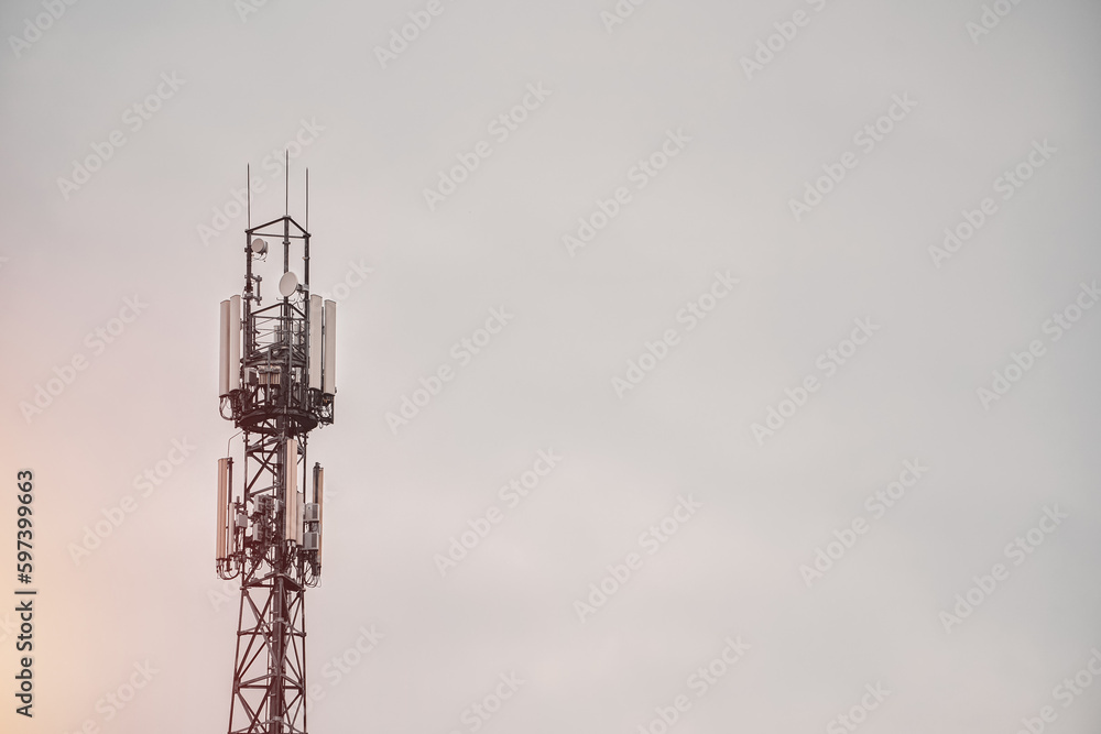 A cell phone tower with a dark sky behind it. A cell phone tower with a dark sky behind it.