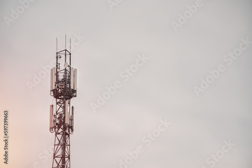 A cell phone tower with a dark sky behind it.