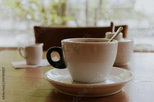 Cup of coffee with milk. Morning coffee in cafe. Coffeehouse interior. Hot drinks concept. Espresso with milk sauce and spoon. Coffee time. Americano with milk.
