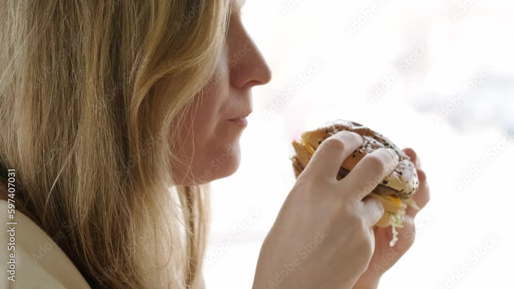 side view woman eating Big burger in fast food Restaurant, unhealthy food, diet side view woman eating Big burger in fast food Restaurant, unhealthy food, diet
