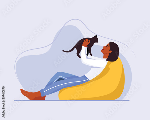 dark-skinned girl with short hair sits on a bean bag chair with a cat