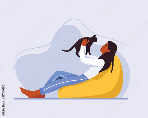 dark-skinned girl with long hair sits on a bean bag chair with a cat	