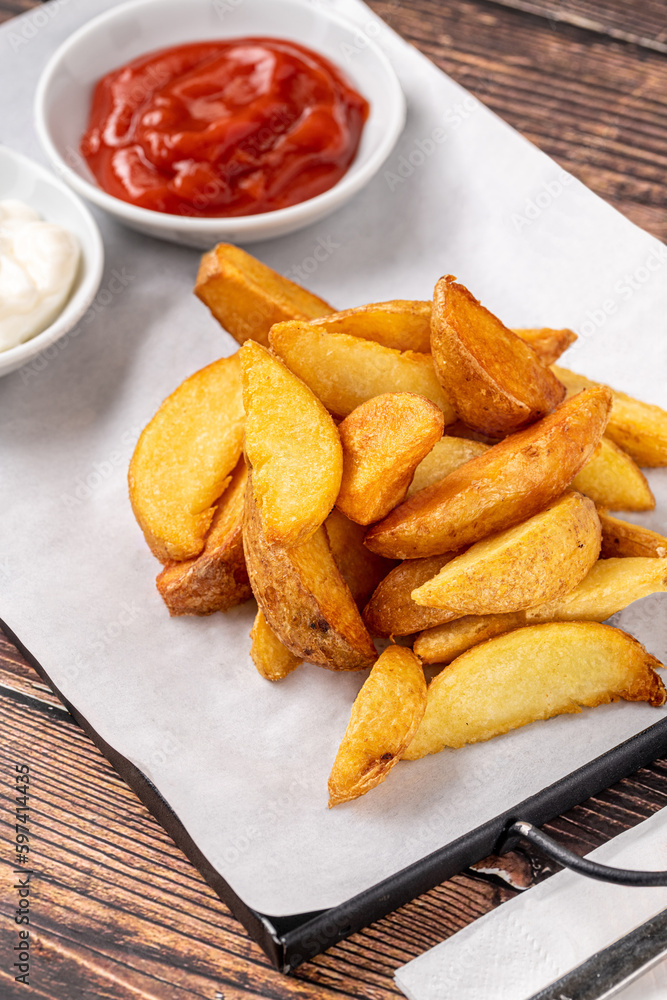 Potato wedges with ketchup and mayonnaise on wooden table Potato wedges with ketchup and mayonnaise on wooden table