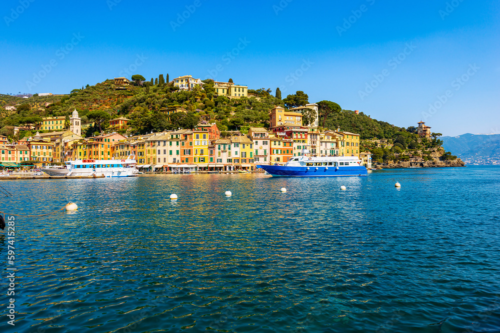 Fototapeta premium Tourist ferries in the famous village of Portofino, luxury tourist resort in Genoa Province, Liguria, Italy, Europe. Port and colorful houses, Mediterranean sea (Ligurian sea).
