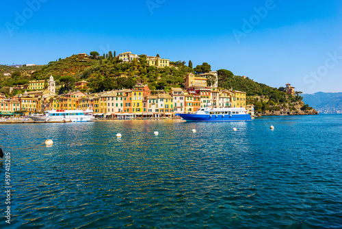 Tourist ferries in the famous village of Portofino, luxury tourist resort in Genoa Province, Liguria, Italy, Europe. Port and colorful houses, Mediterranean sea (Ligurian sea).