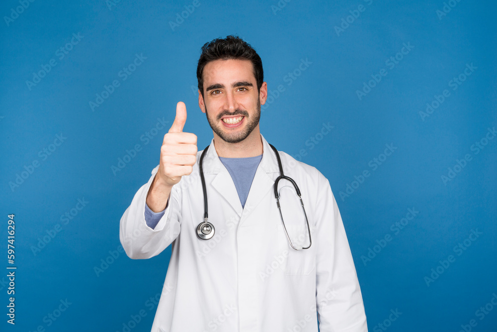 Smiling young doctor with thumbs up looking at the camera Smiling young doctor with thumbs up looking at the camera