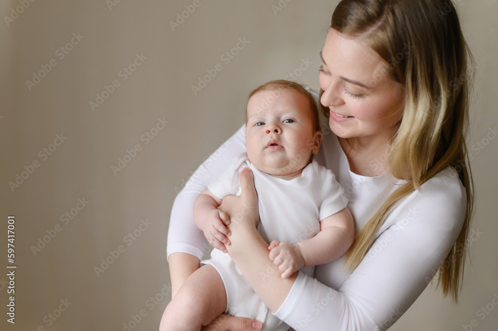 A loving mother holds and hugs her baby, a mother looks at her child with love and tenderness. The concept of motherhood, maternity leave, childcare and care, childhood, children day. A loving mother holds and hugs her baby, a mother looks at her child with love and tenderness. The concept of motherhood, maternity leave, childcare and care, childhood, children day.