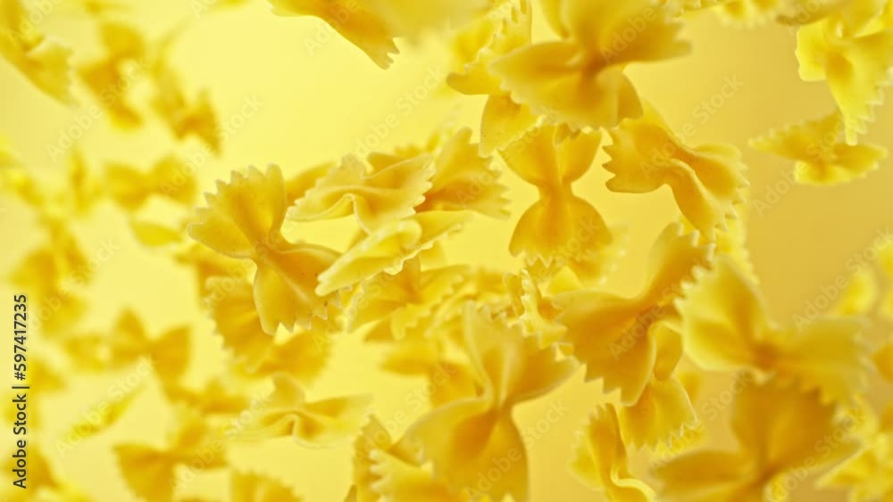 Super slow motion of flying uncooked Italian pasta farfalle. Filmed on high speed cinema camera, 1000 fps, placed on high speed cine bot, following the object. Speed ramp effect. Super slow motion of flying uncooked Italian pasta farfalle. Filmed on high speed cinema camera, 1000 fps, placed on high speed cine bot, following the object. Speed ramp effect.