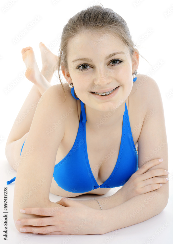 Cheerful happy smiling teen girl wearing blue bikini lying in front of  white background isolated in studio Stock Photo