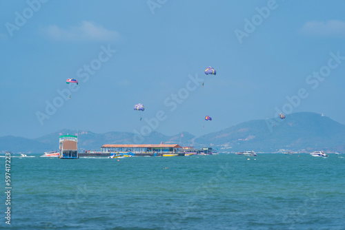 People flying in a colorful parachute or parasail together with blue sky and clouds in freedom and travel concept. photo