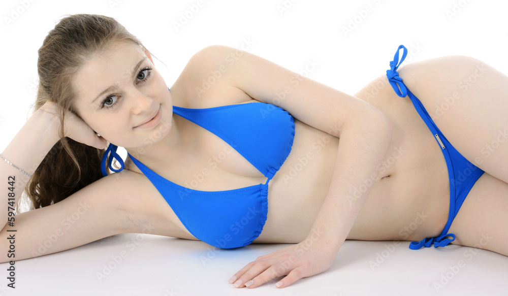 Beautiful teenage girl wearing blue bikini lying in front of white  background isolated in studio Stock Photo