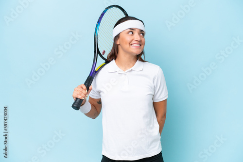 Young tennis player woman isolated on blue background thinking an idea while looking up © luismolinero