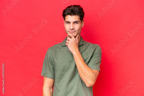 Young caucasian handsome man isolated on red background thinking