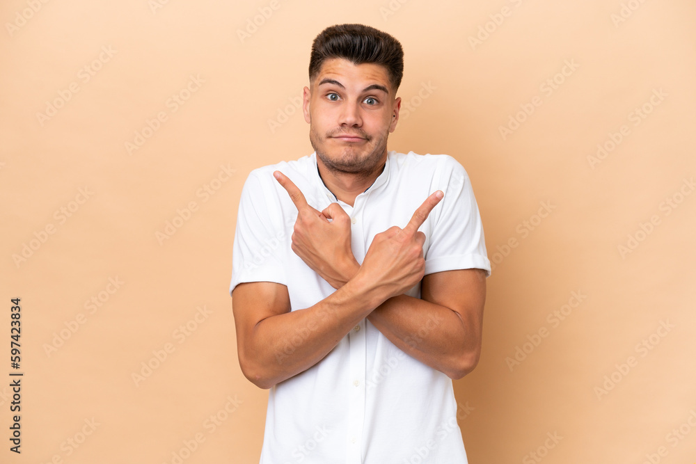 Young caucasian man isolated on beige background pointing to the laterals having doubts Young caucasian man isolated on beige background pointing to the laterals having doubts