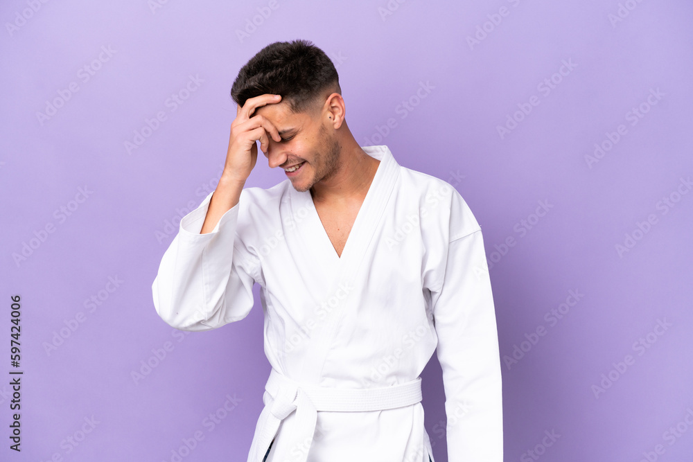 Young caucasian man doing karate isolated on purple background laughing Young caucasian man doing karate isolated on purple background laughing