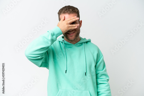 Young handsome caucasian man isolated on white background covering eyes by hands and smiling