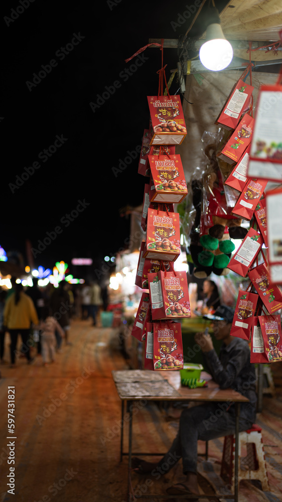 Cambodian night market stall with snacks on display and people walking in the background