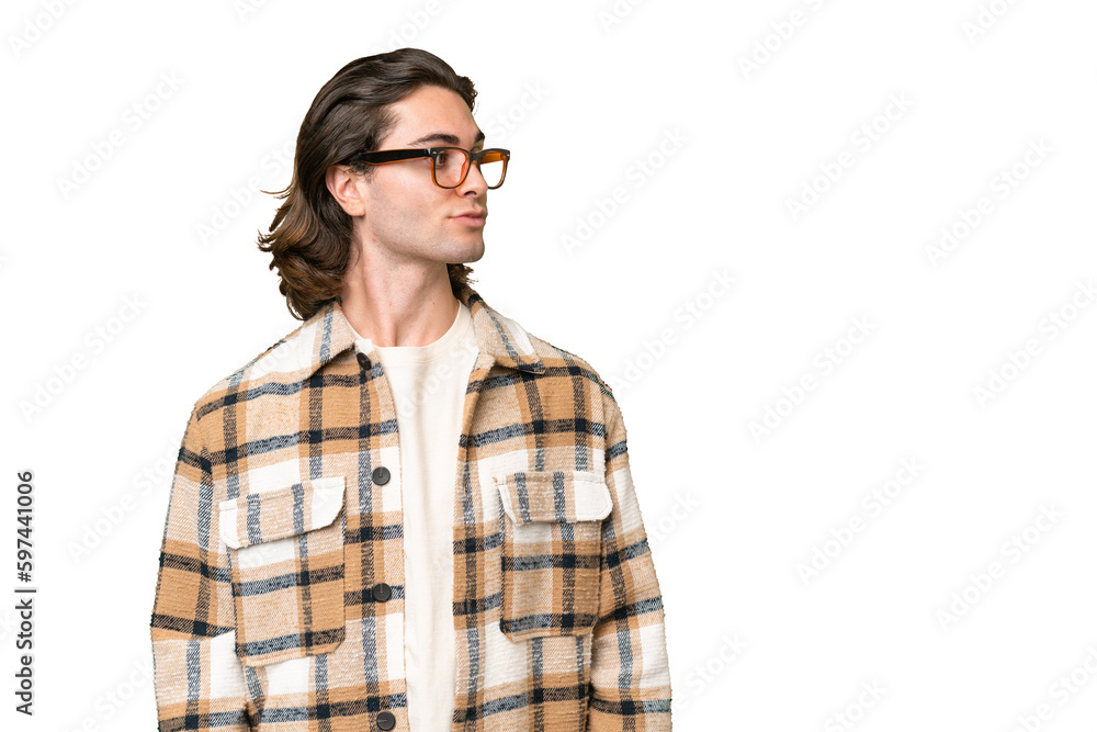 Young caucasian man isolated on green chroma background looking to the side
