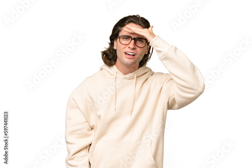 Young caucasian man isolated on green chroma background looking far away with hand to look something