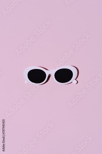White round glasses on a pink background in a minimalist style. Flat lay, top view.
