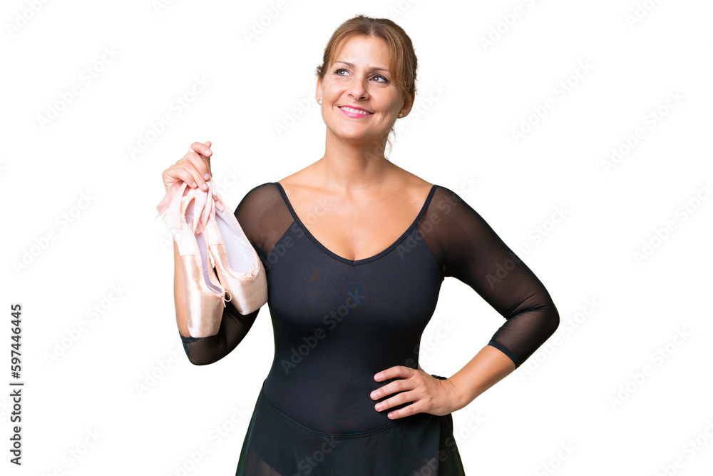 Middle-aged caucasian woman practicing ballet over isolated background posing with arms at hip and smiling Middle-aged caucasian woman practicing ballet over isolated background posing with arms at hip and smiling