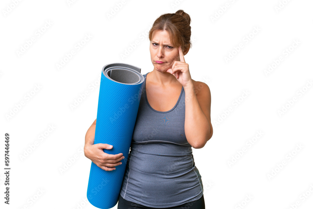 Middle-aged sport woman going to yoga classes while holding a mat over isolated background thinking an idea Middle-aged sport woman going to yoga classes while holding a mat over isolated background thinking an idea