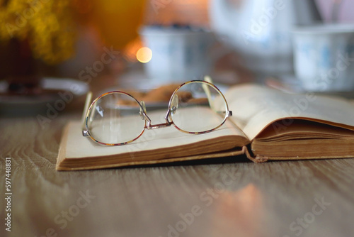 Cup of tea or coffee, plate of cookies, cup of blueberries, plate of chocolate, glass of juice, book, reading glasses, teapot, flowers and lit candles on the table. Brunch or afternoon tea concept.