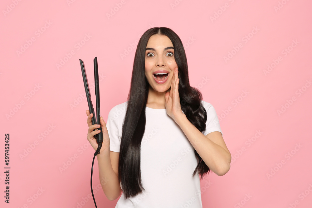 Beautiful emotional woman with hair iron on pink background Beautiful emotional woman with hair iron on pink background