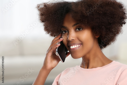 Smiling African American woman talking on smartphone at home. Space for text