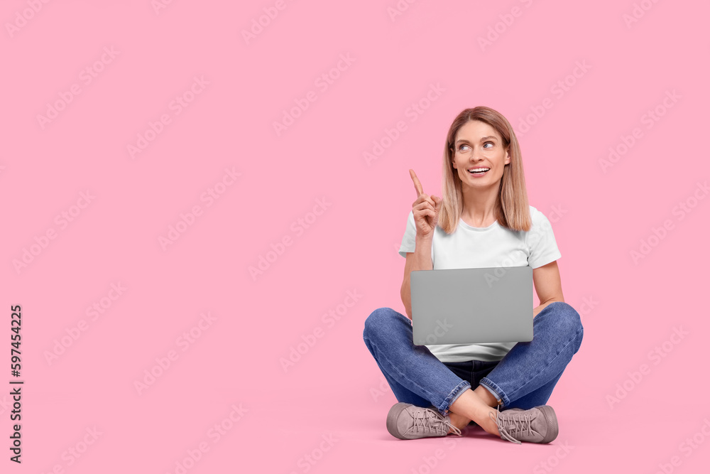 Happy woman with laptop pointing at something on pink background. Space for text Happy woman with laptop pointing at something on pink background. Space for text